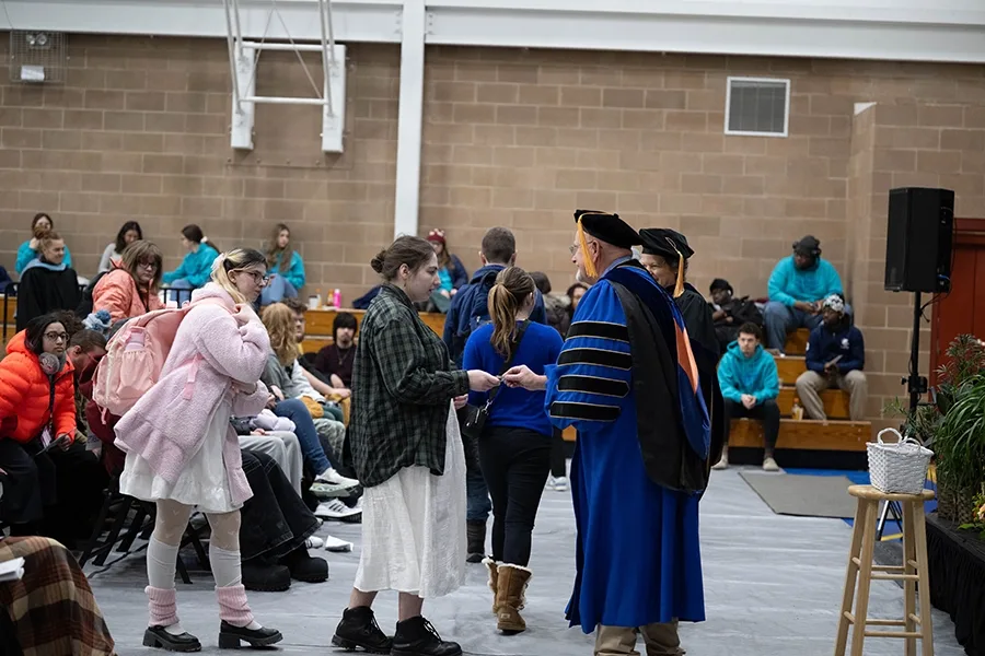 Students receiving coins from President Jim Dlugos