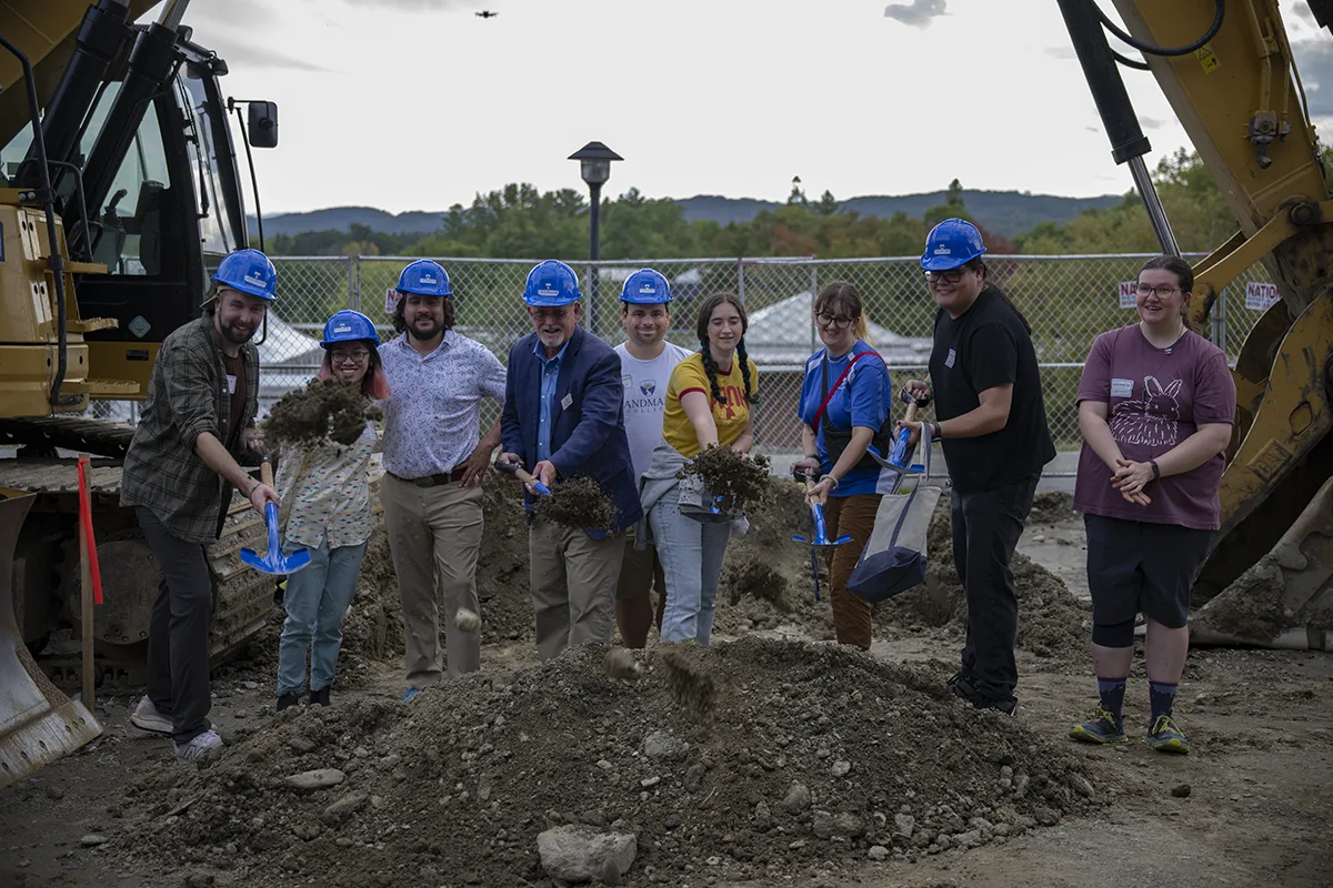 Landmark's President Dlugos with eight students wearing blue hardhats and shoveling dirt.