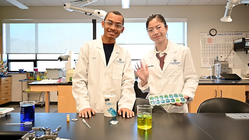 Two Landmark College students in dresses in white coats in one of the chemistry labs on campus.