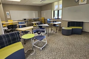 Colorful lime green and dark blue furniture in a classroom with tan floors.
