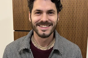 Man with brown hair and brown beard facing camera and smiling.