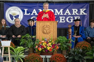 A person has their hands over their heart as they give a speech while standing at a podium.