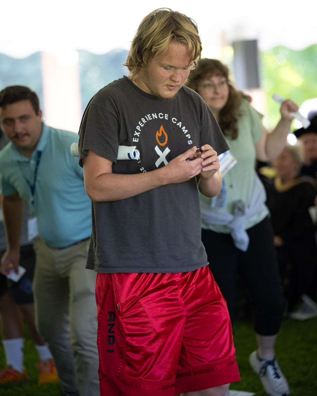 A male student in red shorts looking at a coin