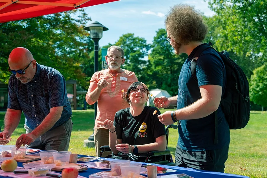 Four people at an apple and cheese tasting booth.