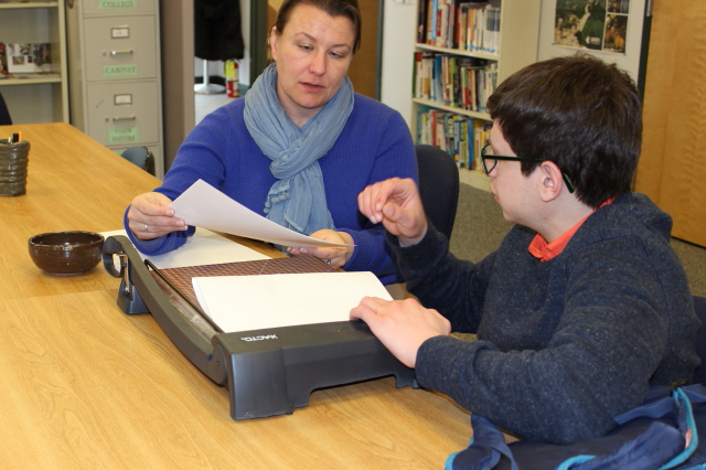 Ben Raskin-Gross and Financial Aid staffer with paper cutter.