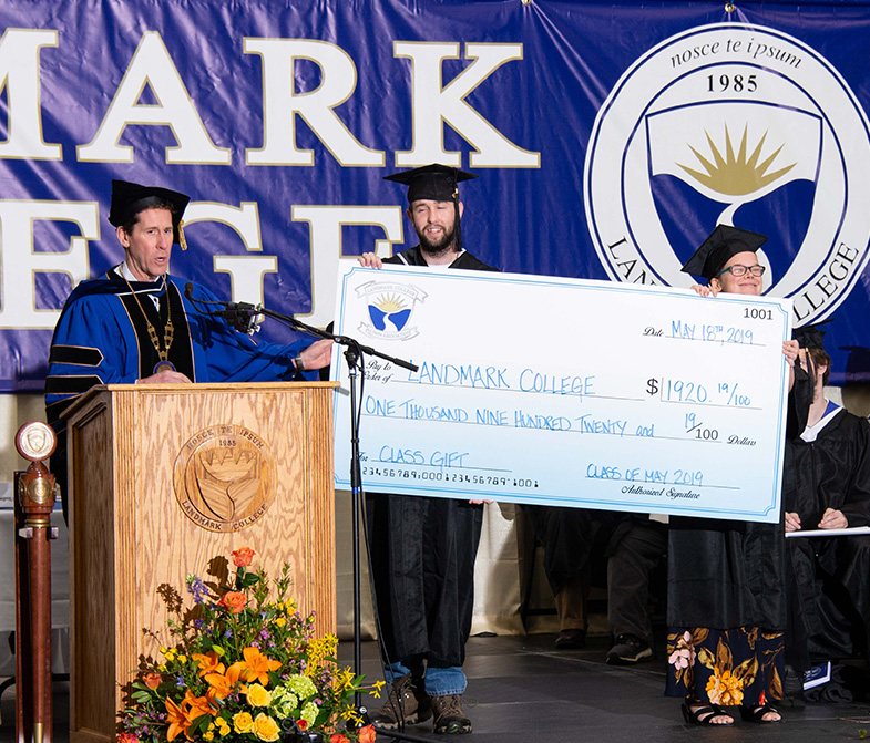 Two graduates holding a large check for $1,920.