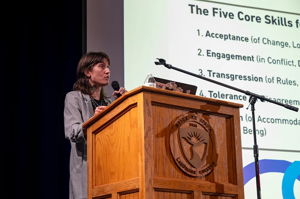 A person stands at a podium while giving a presentation on autistic unmasking.