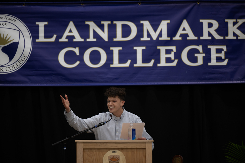 Picture of male student at podium gesturing with his right hand.