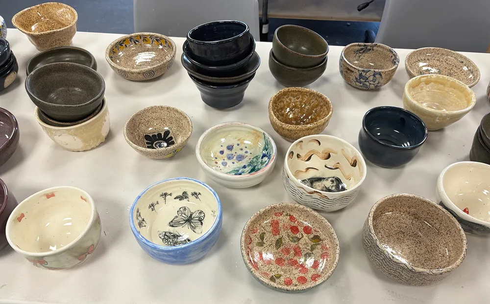 Finished bowls with designs of butterflies and other images from nature are displayed on a table.
