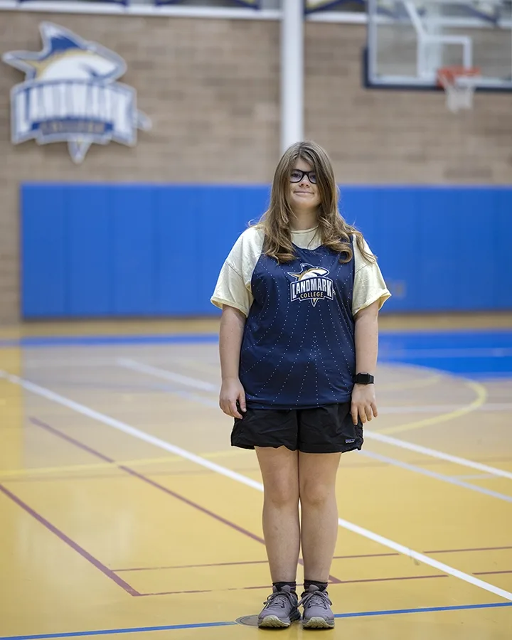 Fiona Mann stands in an athletic uniform in the gymnasium inside the Landmark College Click Center.