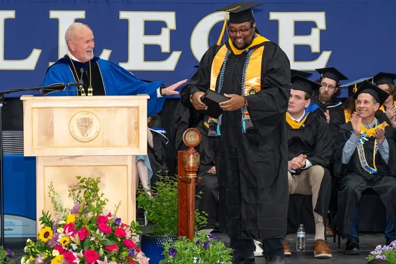 President Dlugos at the podium with Anastasio Bonhomme.