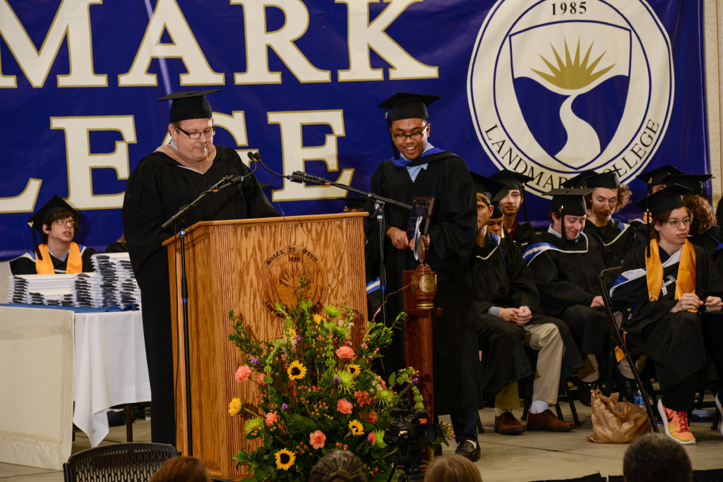 Ghiaz Badruddin at podium with Michael Luciani on stage at graduation.