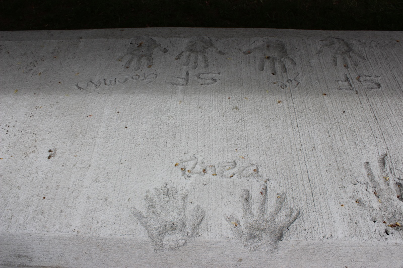 Handprints in concrete with names written above them.