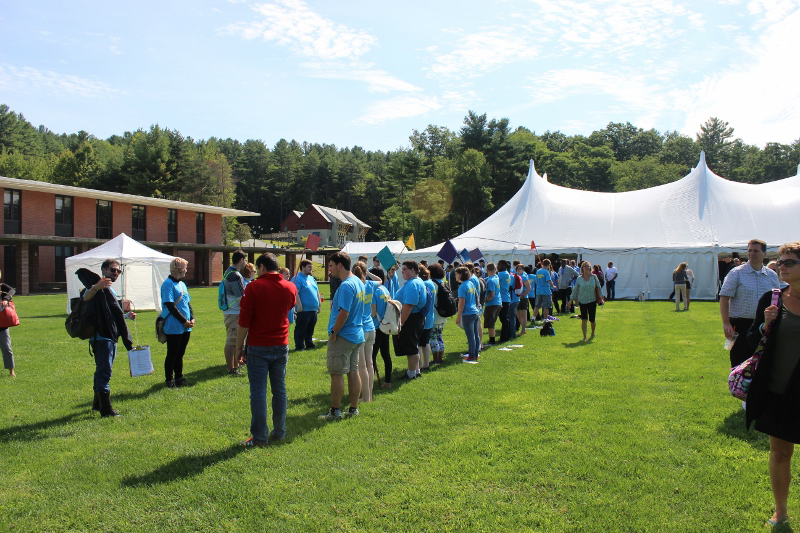 A double line of people waits outside a large tent on the Landmark College quad.