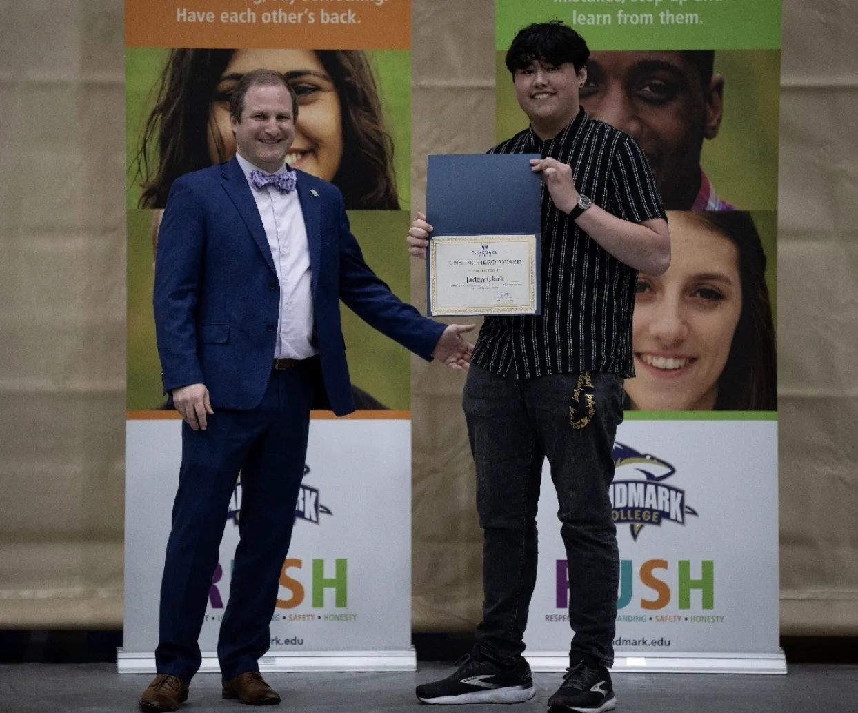 Jaden Clark holding his award with presenter Craig Marcus to the left.