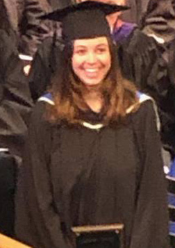 Lydia Allen standing in cap and gown holding her award.