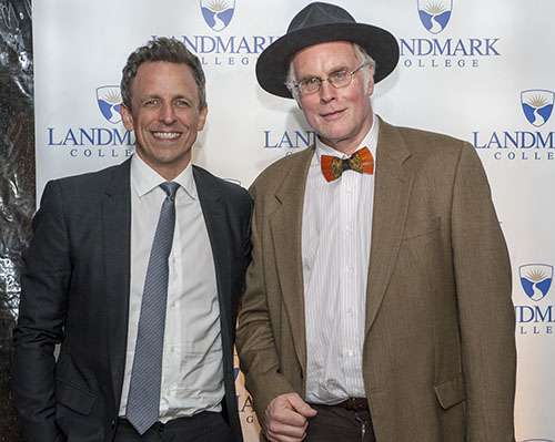 Seth Meyers posing for a photo next to John Elder Robison wearing a red bowtie and black brim hat.
