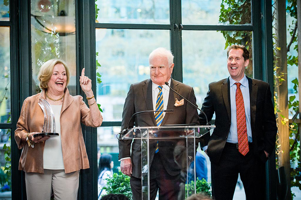 Three people standing at a clear plexiglass podium.