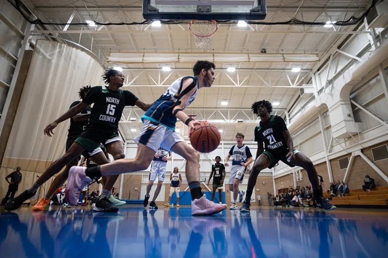 Landmark College men's basketball athlete dribbling ball around defense.