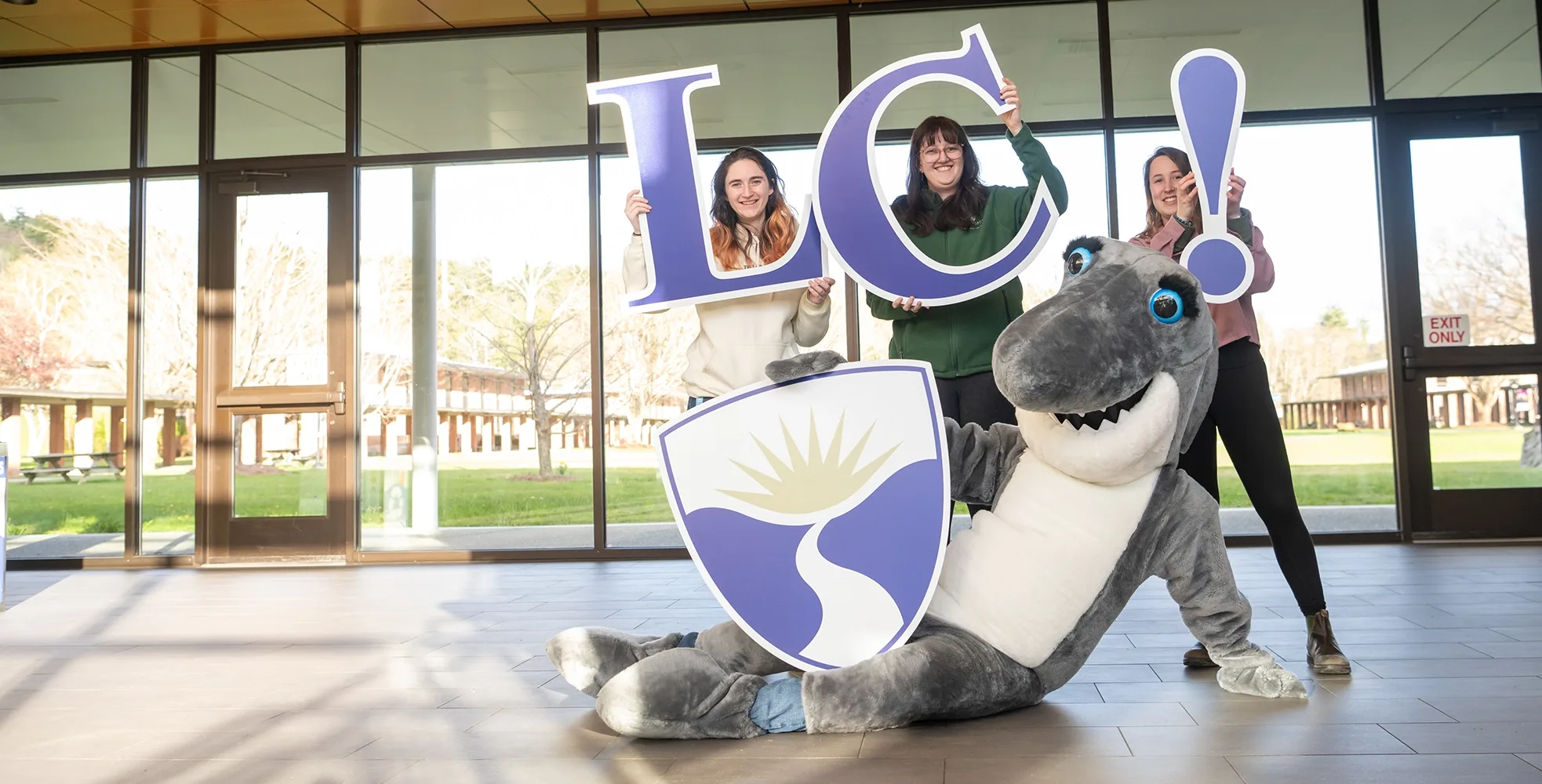 Landmark College students and beloved mascot, Finn, show off the College's acronym, L, C, our shield, and an exclamation point. Photo by Matt Lester.