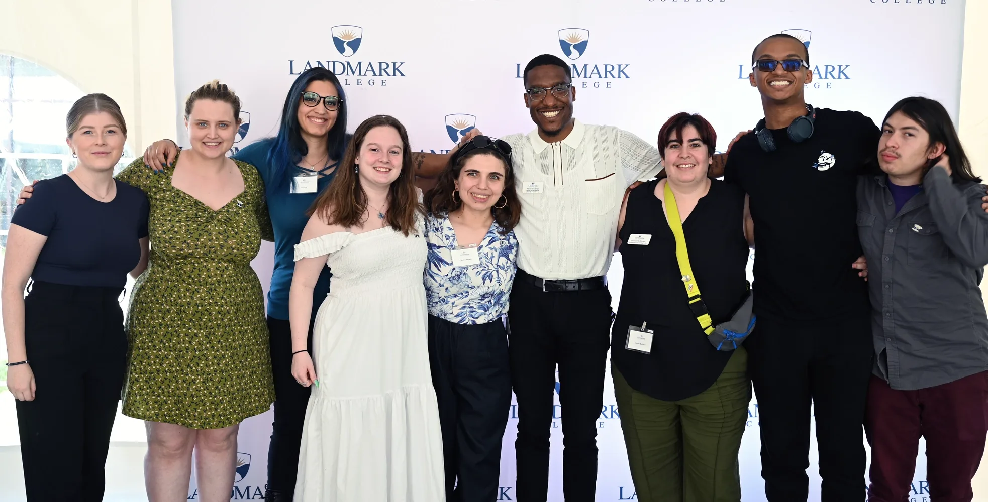 A group of Landmark alumni posing for photo in front of step and repeat.