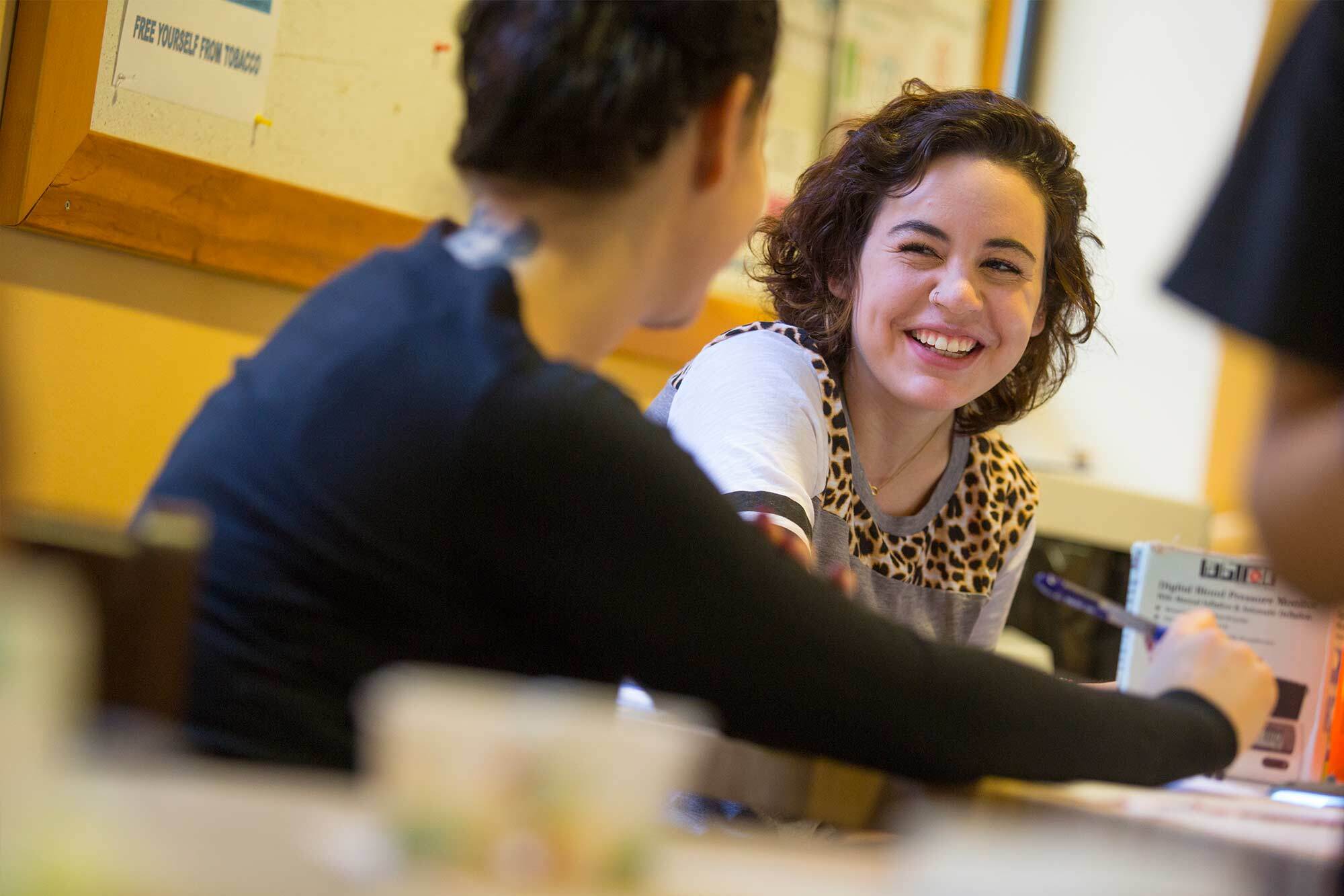Two students smiling and facing each other in a classroom
