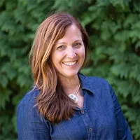 A headshot of Cynthia Ludlam in front of arborvitae. 