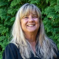 A headshot of Kate Wilson in front of arborvitae. 