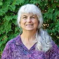 A headshot of Lee Crocker in front of arborvitae. 