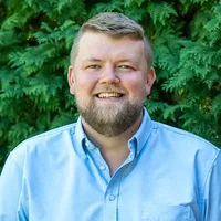A headshot of Lachlan Francis in front of arborvitae. 